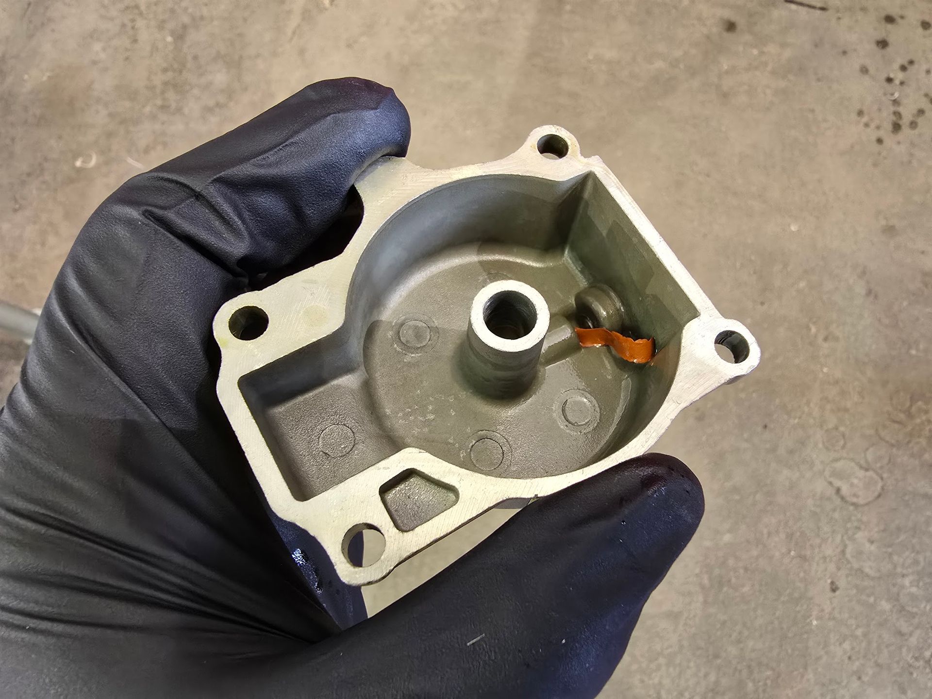 Debris from a failed aftermarket fuel pump clogging an outboard carburetor passage during fuel system repair at Anchor Marine in Menomonie Wisconsin serving the Eau Claire boating area