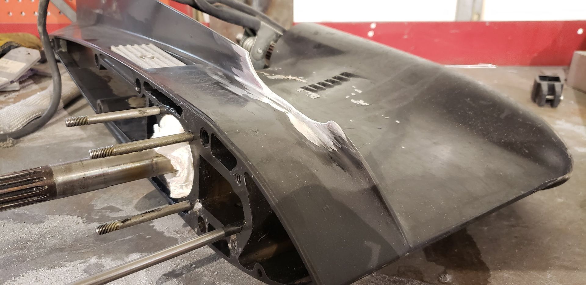 Damaged anti-ventilation plate on Force outboard lower unit before aluminum welding repair at Anchor Marine boat repair shop in Menomonie Wisconsin serving the Eau Claire area