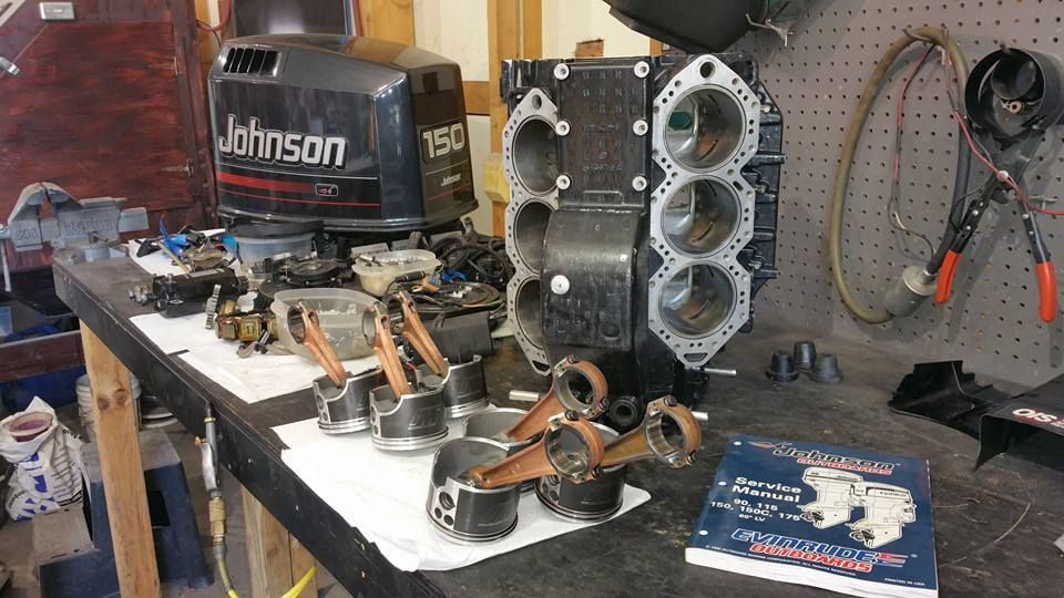 Johnson 150 HP V6 outboard engine powerhead disassembled during complete engine rebuild with pistons, rods, and cylinder block on workbench at Anchor Marine boat repair shop in Menomonie Wisconsin serving the Eau Claire area