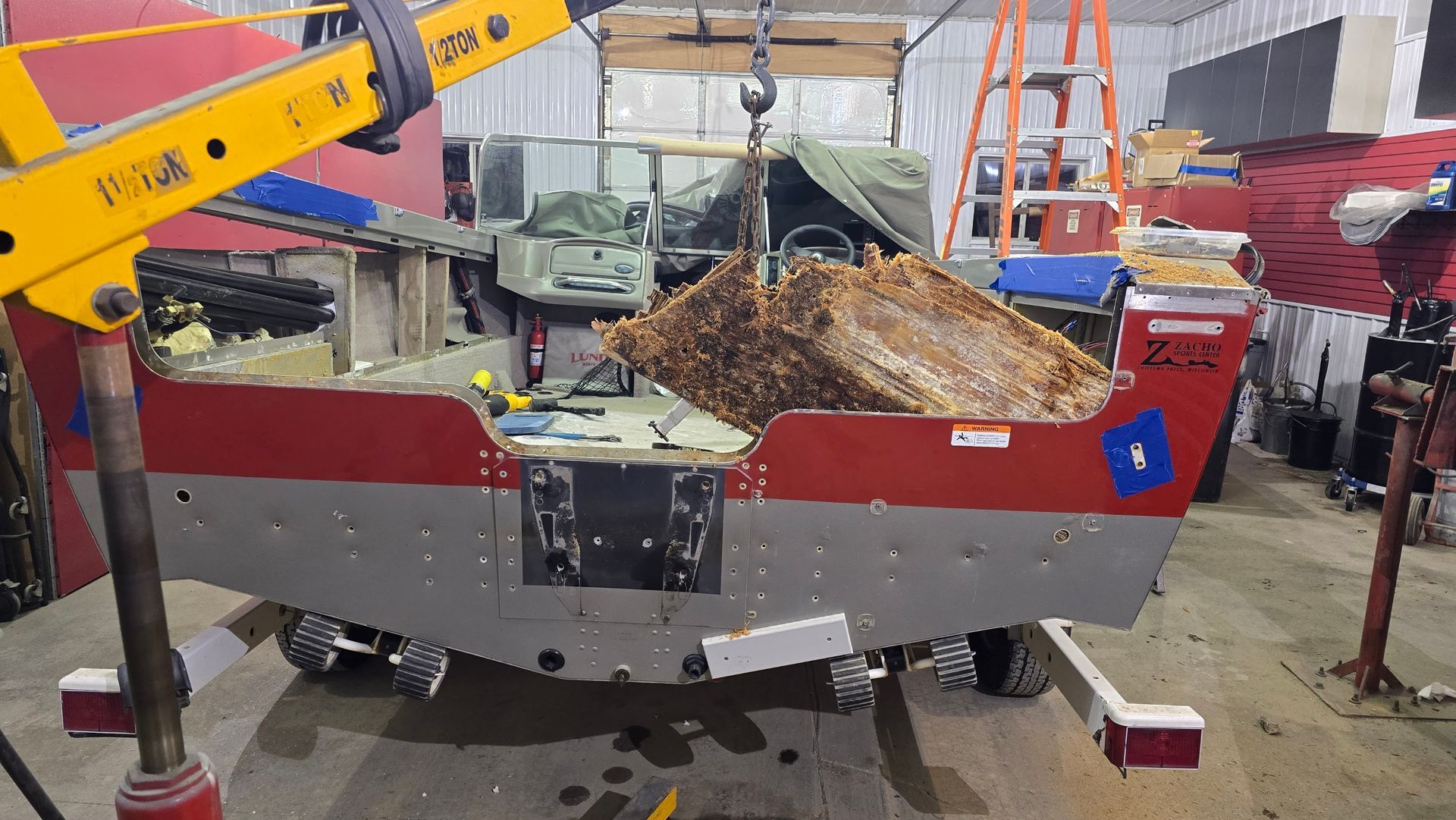 Rotten transom being removed from a Lund aluminum fishing boat during transom repair at Anchor Marine in Menomonie Wisconsin serving the Eau Claire and Chippewa Valley area