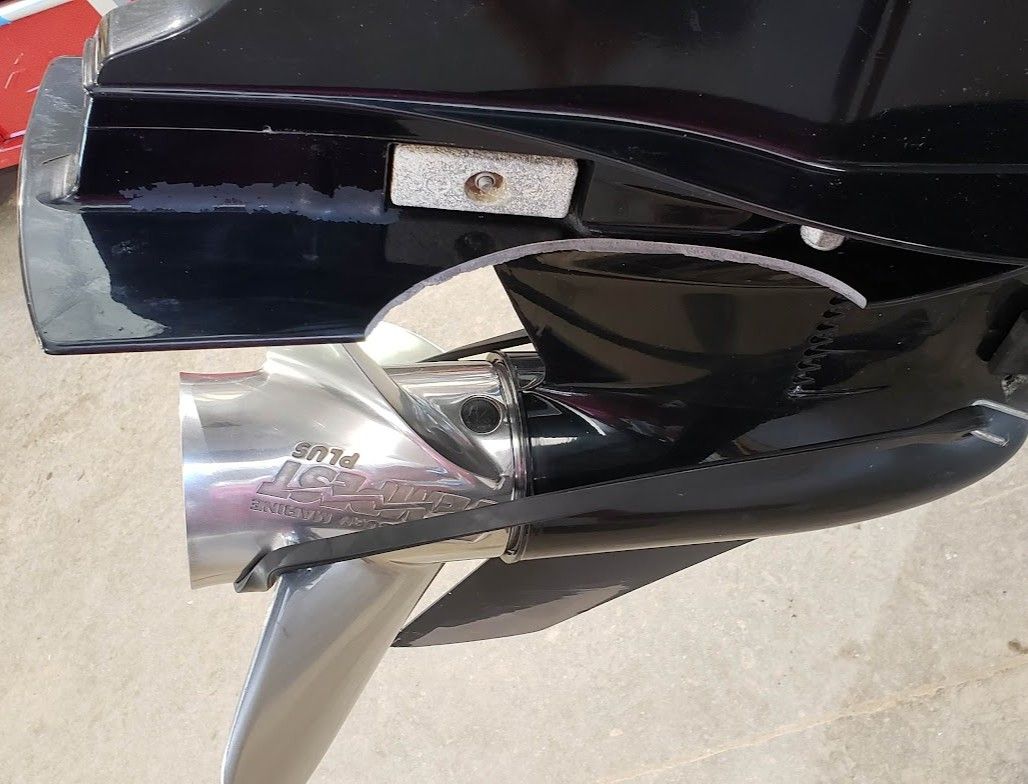 Broken cavitation plate and lower unit fin damage on an outboard motor after hitting a rock, showing aluminum impact damage before cavitation plate repair at Anchor Marine boat repair shop in Menomonie Wisconsin serving the Eau Claire area