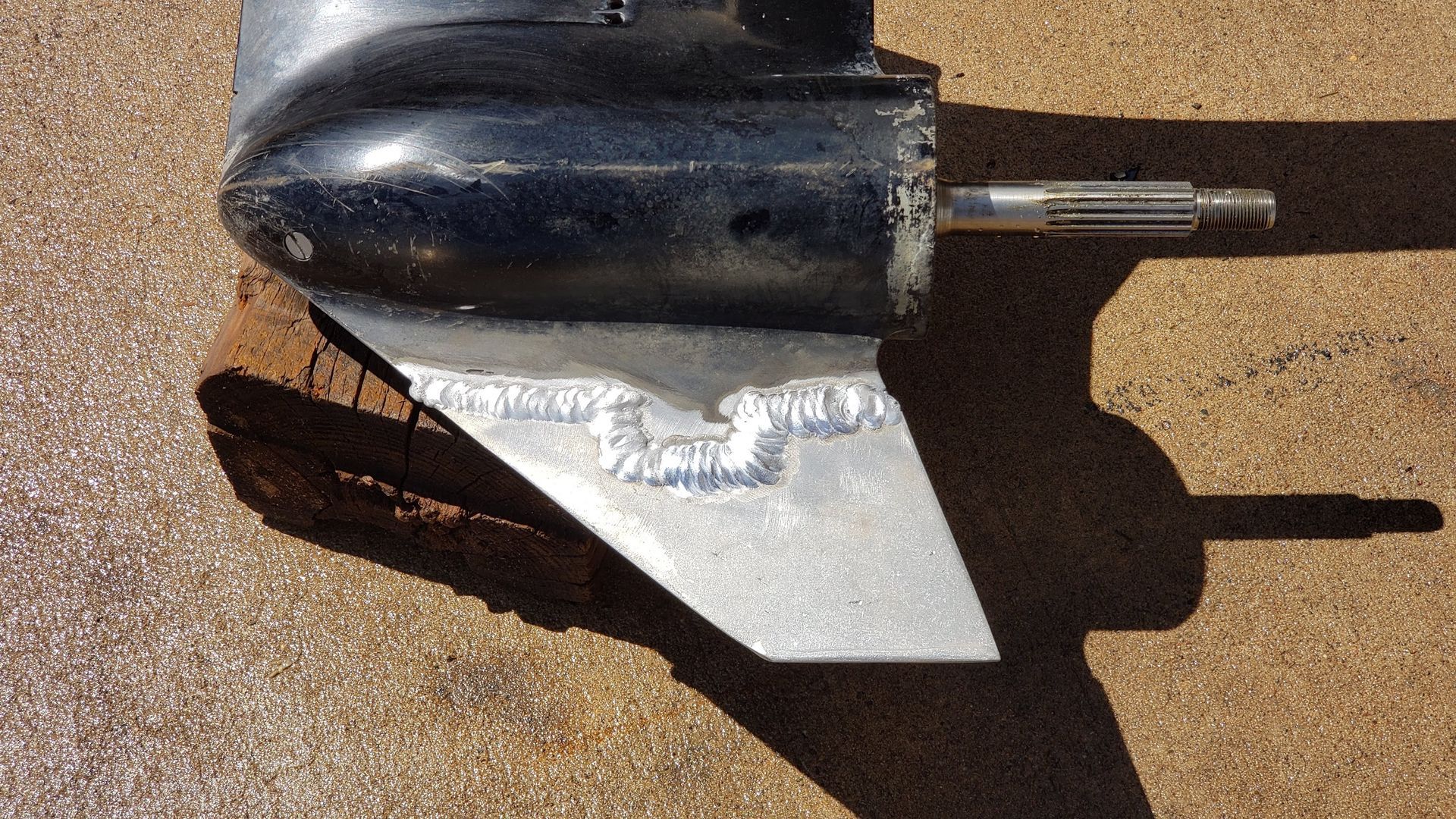 Outboard lower unit skeg rebuilt with aluminum welding after severe impact damage, showing structural skeg repair before finishing and paint at Anchor Marine boat repair shop in Menomonie Wisconsin serving the Eau Claire area