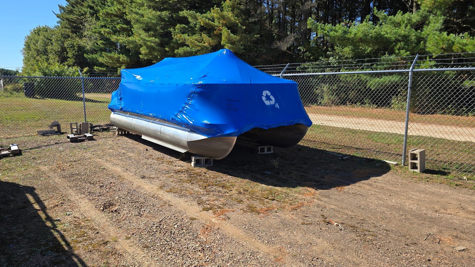 Shrink wrapped pontoon boat stored in secure fenced storage yard at Anchor Marine in Menomonie Wisconsin
