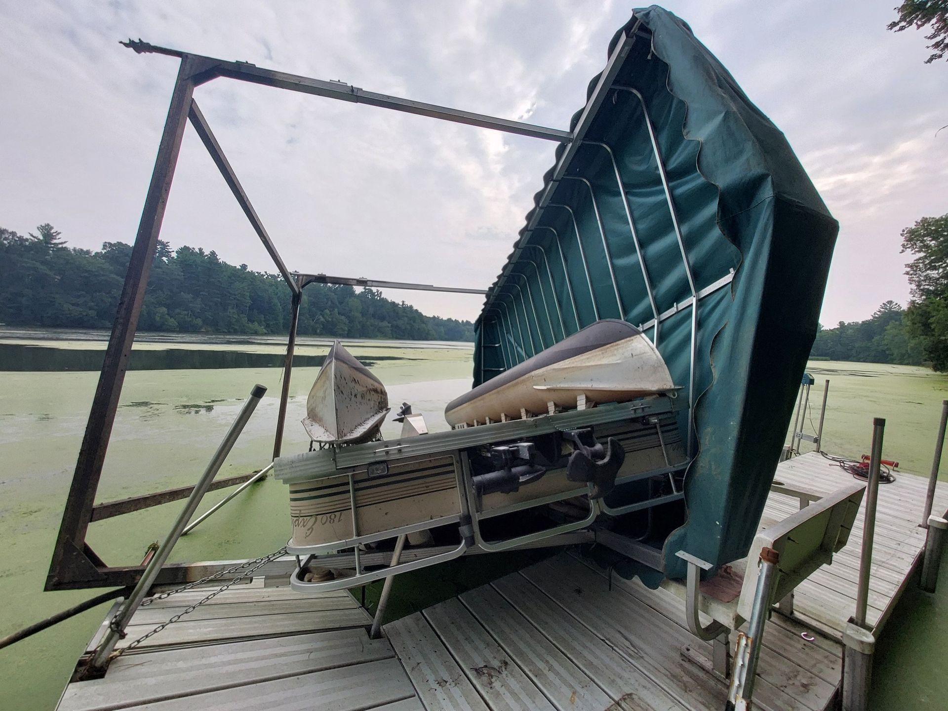 Pontoon boat flipped and damaged boat lift after a summer storm on a Wisconsin lake dock near Eau Claire and Menomonie with repairs and insurance estimates handled by Anchor Marine