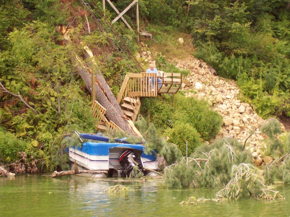 Pontoon boat crushed by a fallen tree after a summer storm on Lake Menomin in Menomonie Wisconsin with storm damage inspection and repair services by Anchor Marine near Eau Claire