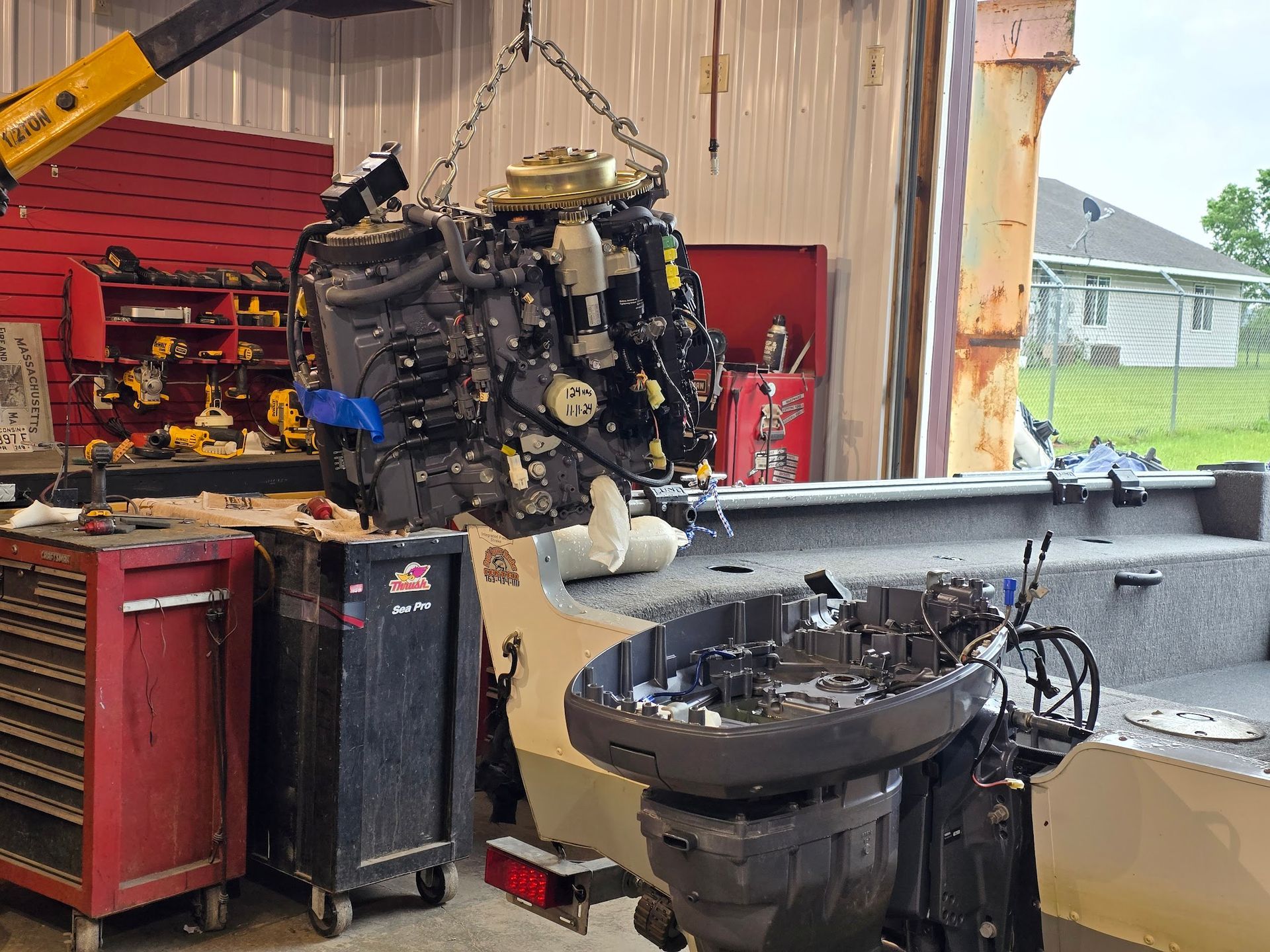 Yamaha 75 HP outboard powerhead being lifted from midsection during engine repair at Anchor Marine boat repair shop in Menomonie Wisconsin serving the Eau Claire area