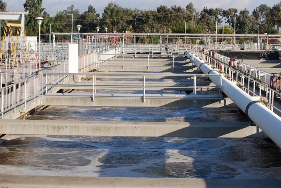 Water treatment tanks and metal walkways in an industrial facility under bright sunlight