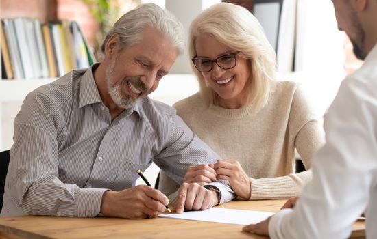 A man and a woman are sitting at a table signing a document.