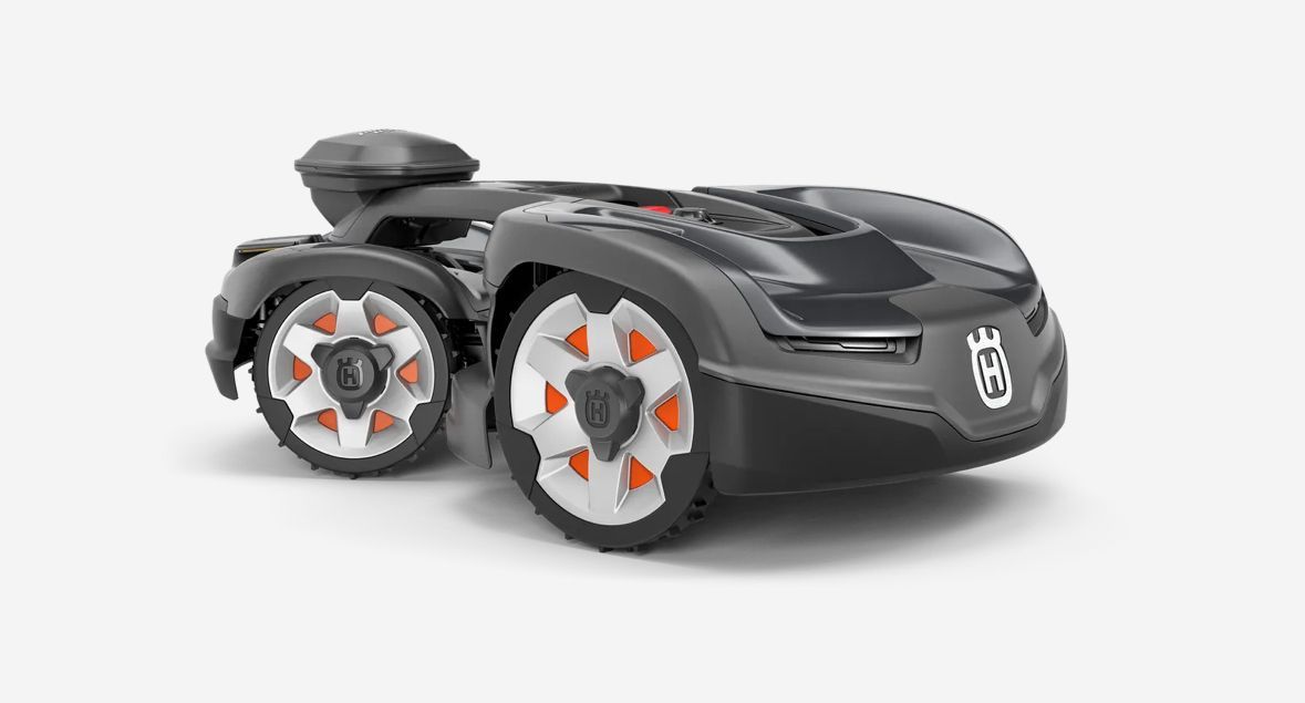 Husqvarna robotic lawnmower, dark gray with orange accents, on a white surface.