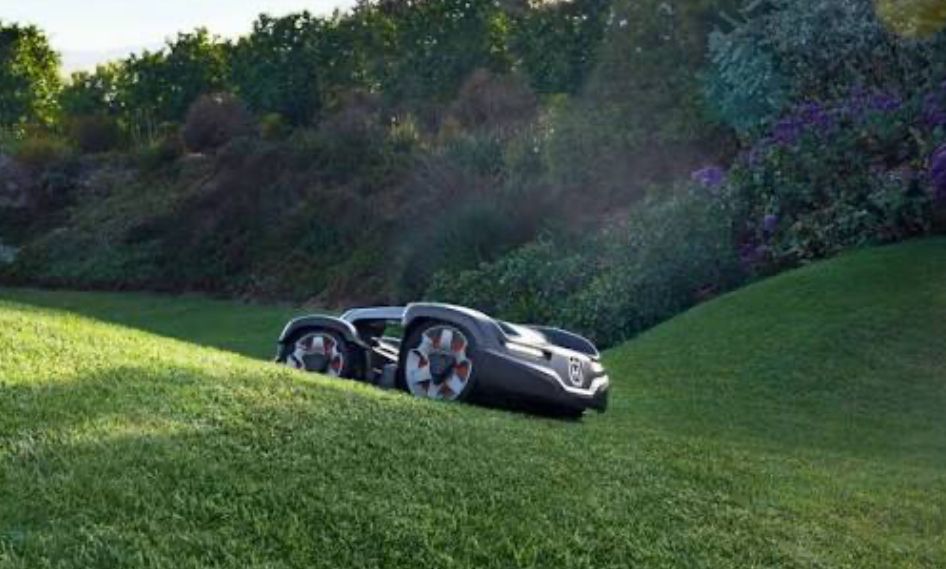 Robotic lawnmower on a green hillside, mowing grass.