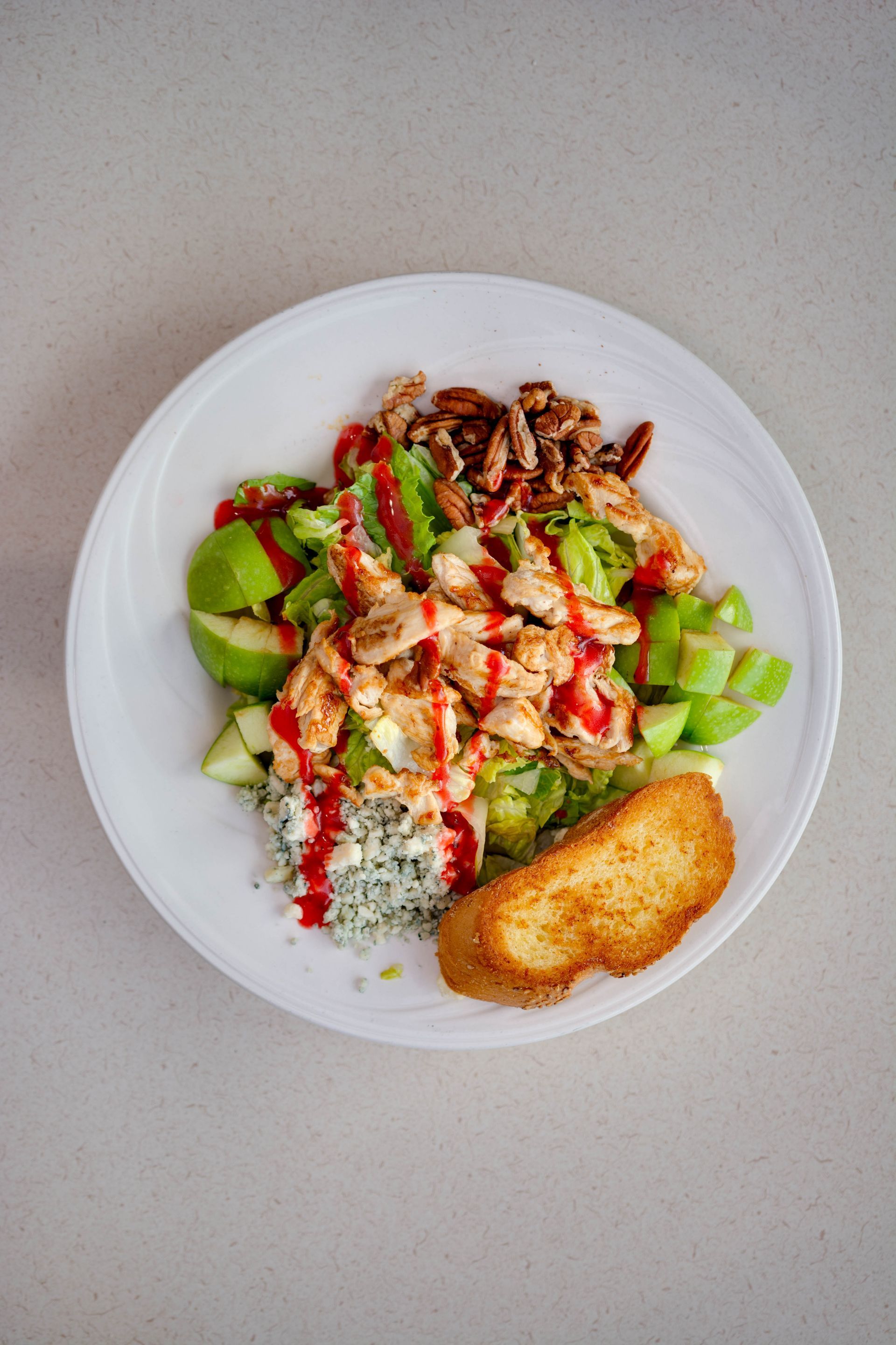 Salad bowl with grilled chicken, avocado, rice, and a breaded croquette on a white plate