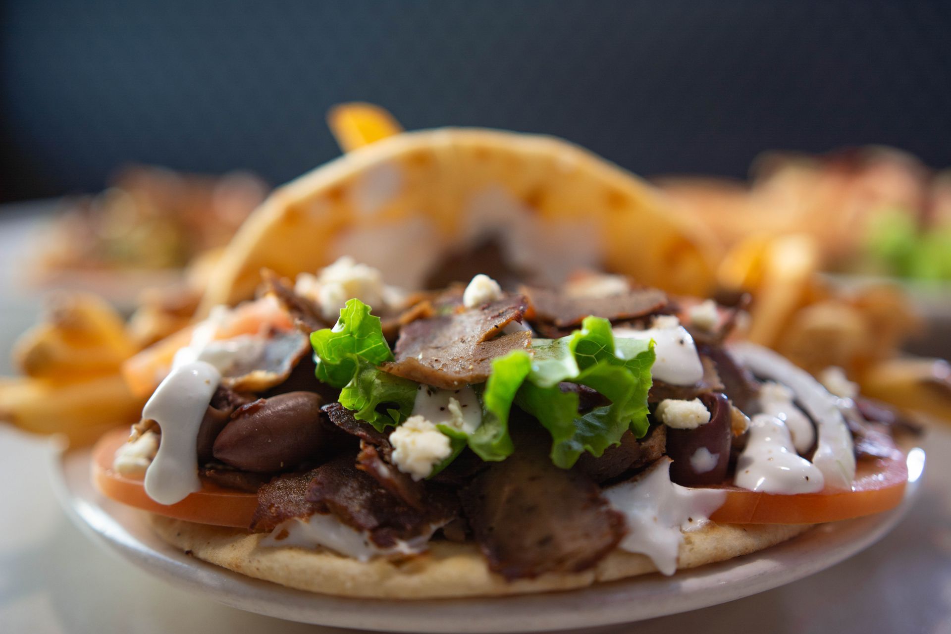 Plate of tacos with grilled meat, cilantro, onions, and white sauce on a blurred background