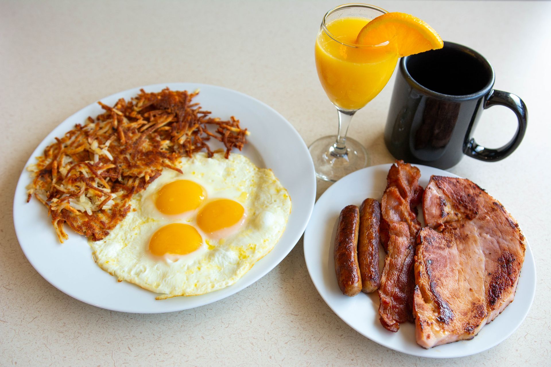 Breakfast plate with eggs, hash browns, bacon, toast, orange juice, and coffee mug