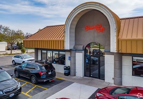 Strip mall storefront with arched entrance, orange roof, and parked cars in front