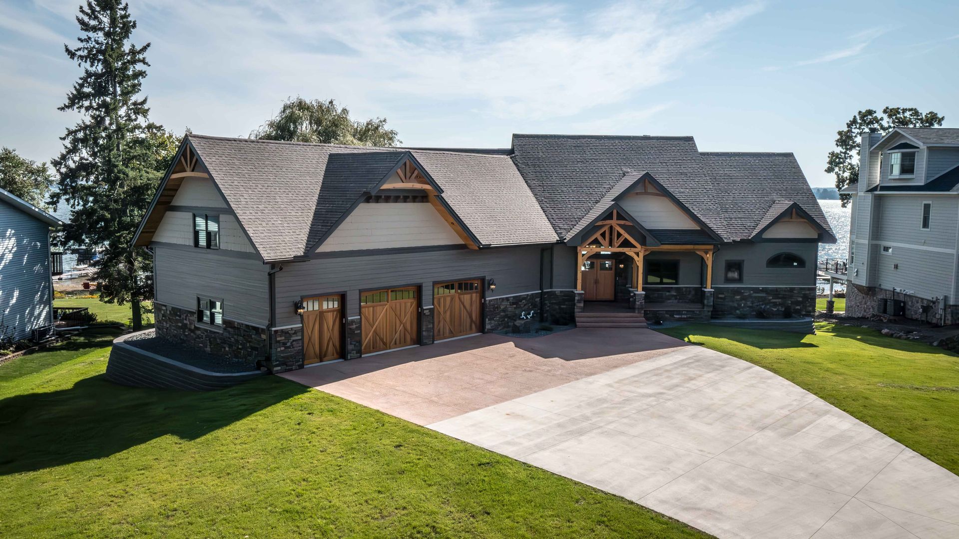 A large house with a multi-gabled roof and three car garage with a stone and wood facade.