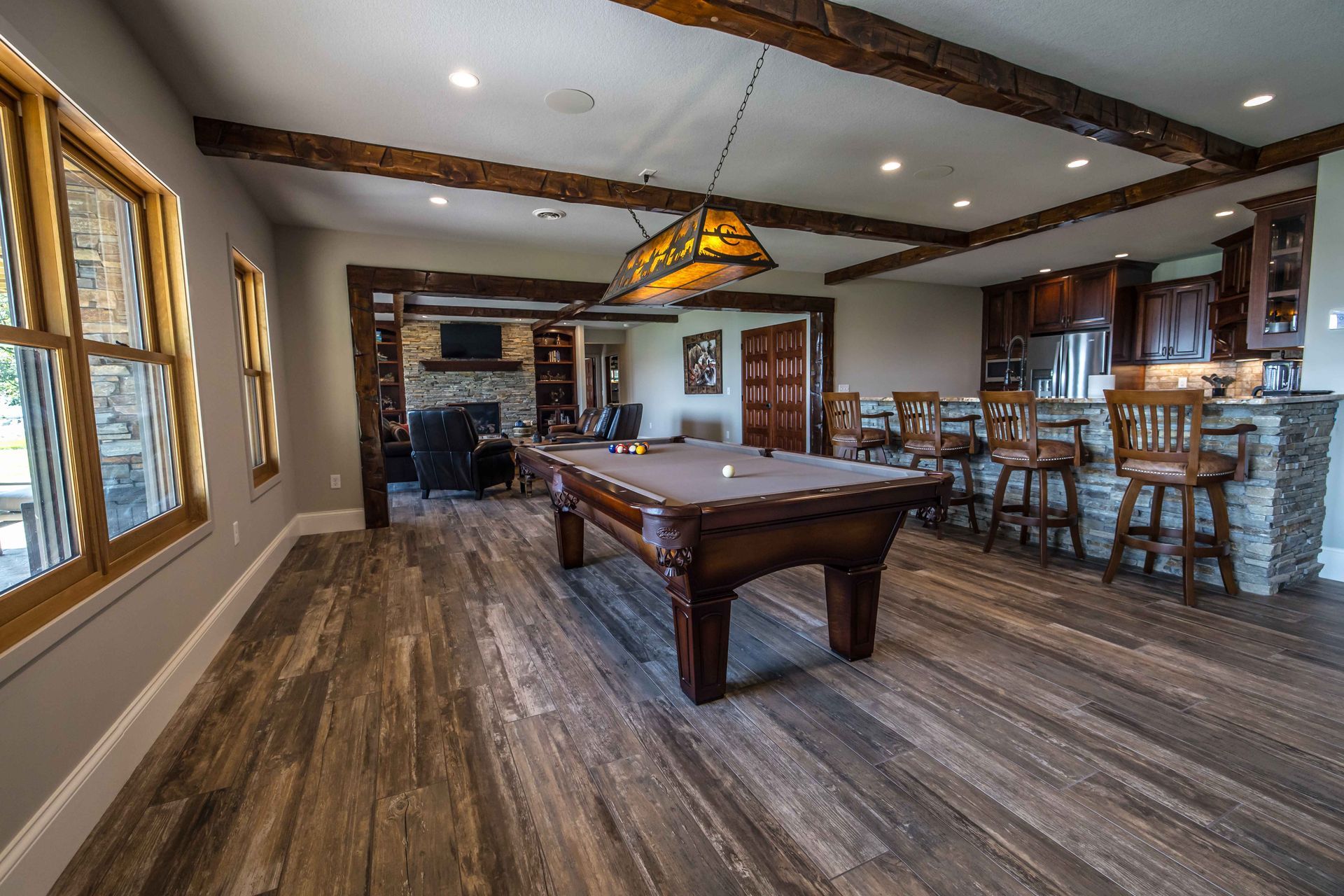 Game room with a pool table, bar, fireplace, and wood-beam ceiling.