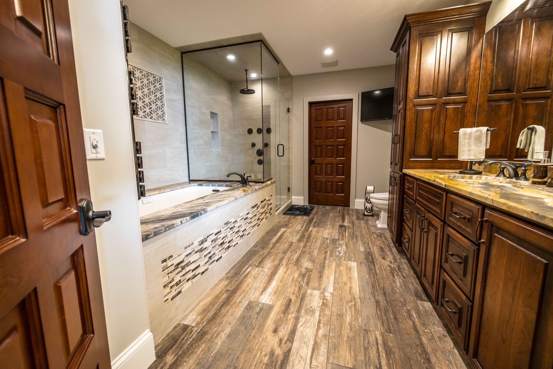 Luxurious bathroom with wood cabinets, tiled shower, and a large bathtub.