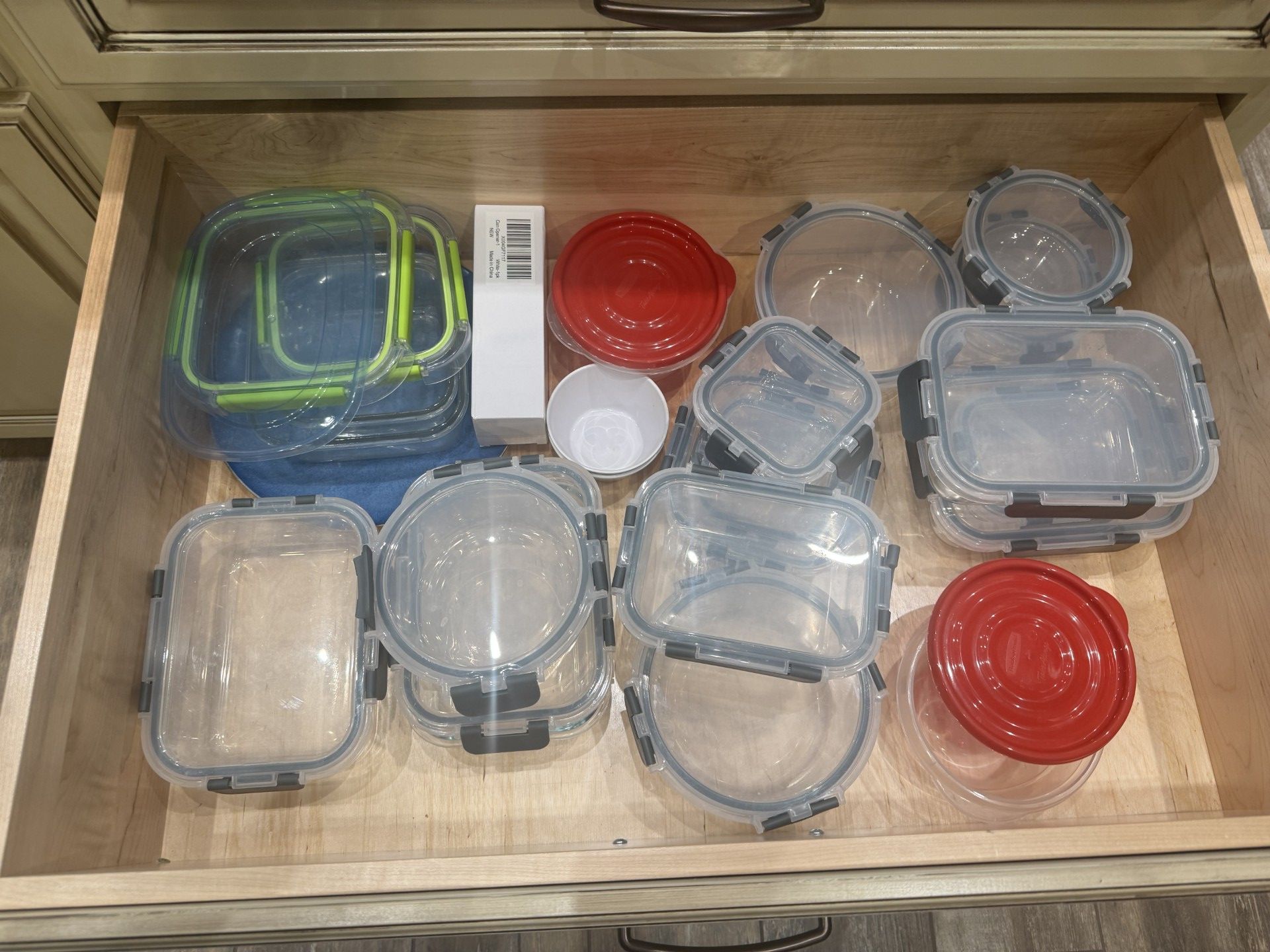 A kitchen drawer filled with various clear and colored food storage containers.