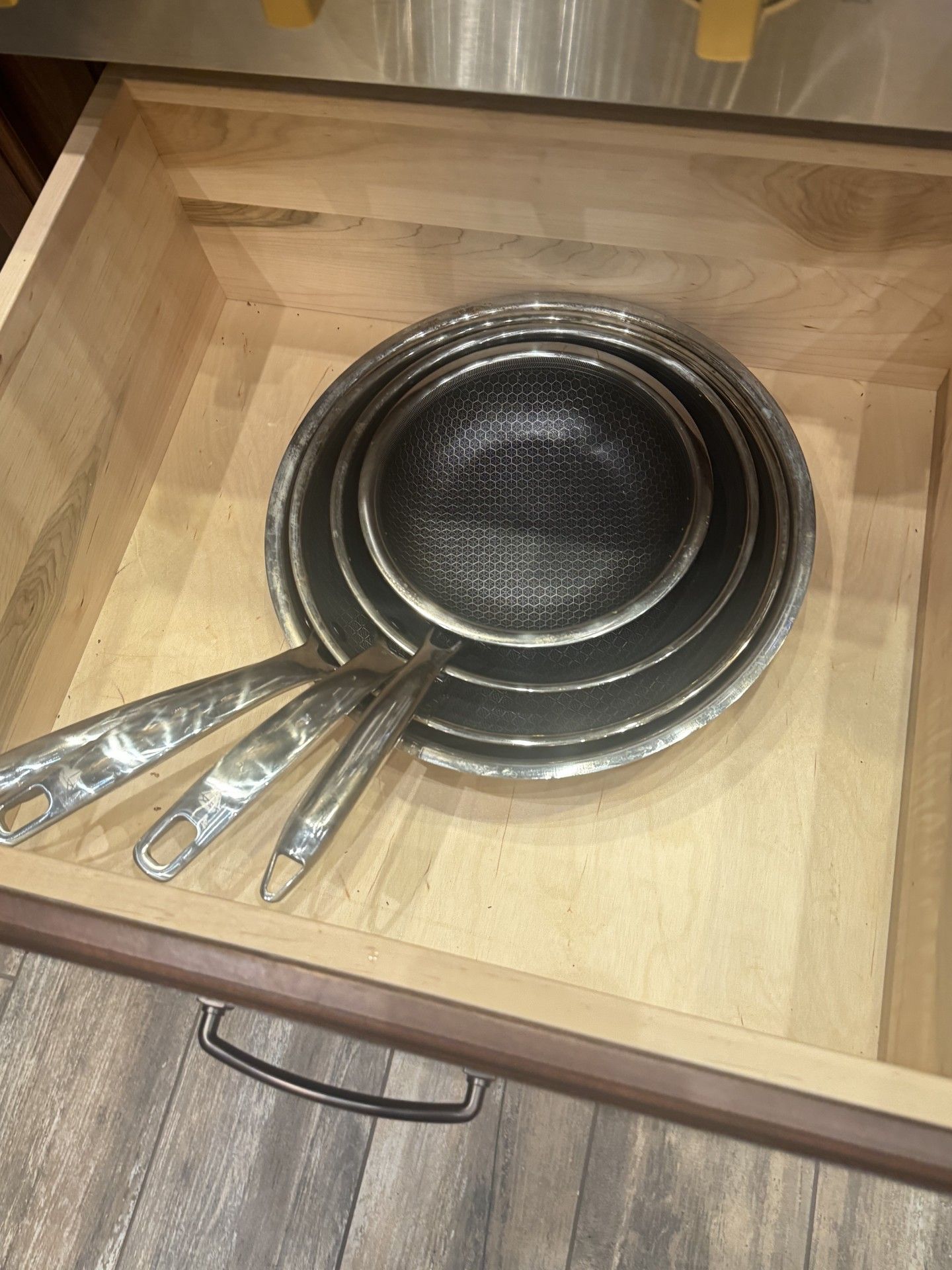 A kitchen drawer containing nested metal strainers and serving spoons.