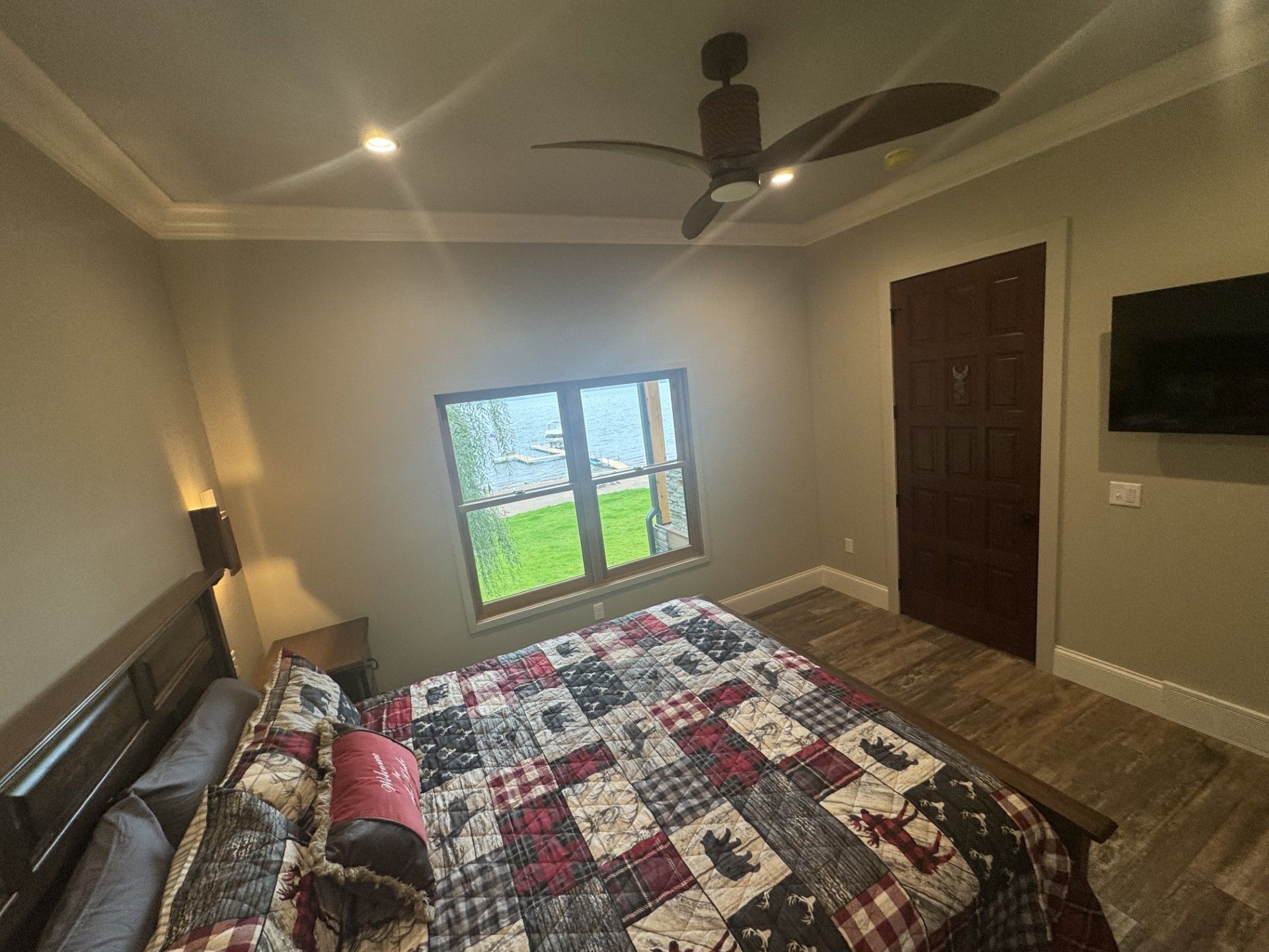 Bedroom with a patchwork quilt on the bed, a window with a view, and a dark wooden door.