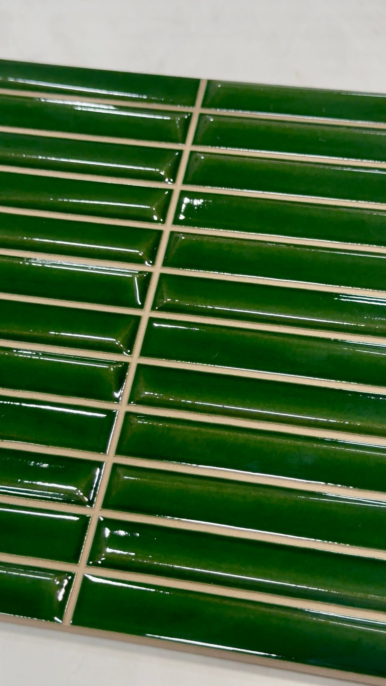 Close-up of green ceramic tiles with white grout lines, forming a diagonal grid pattern.
