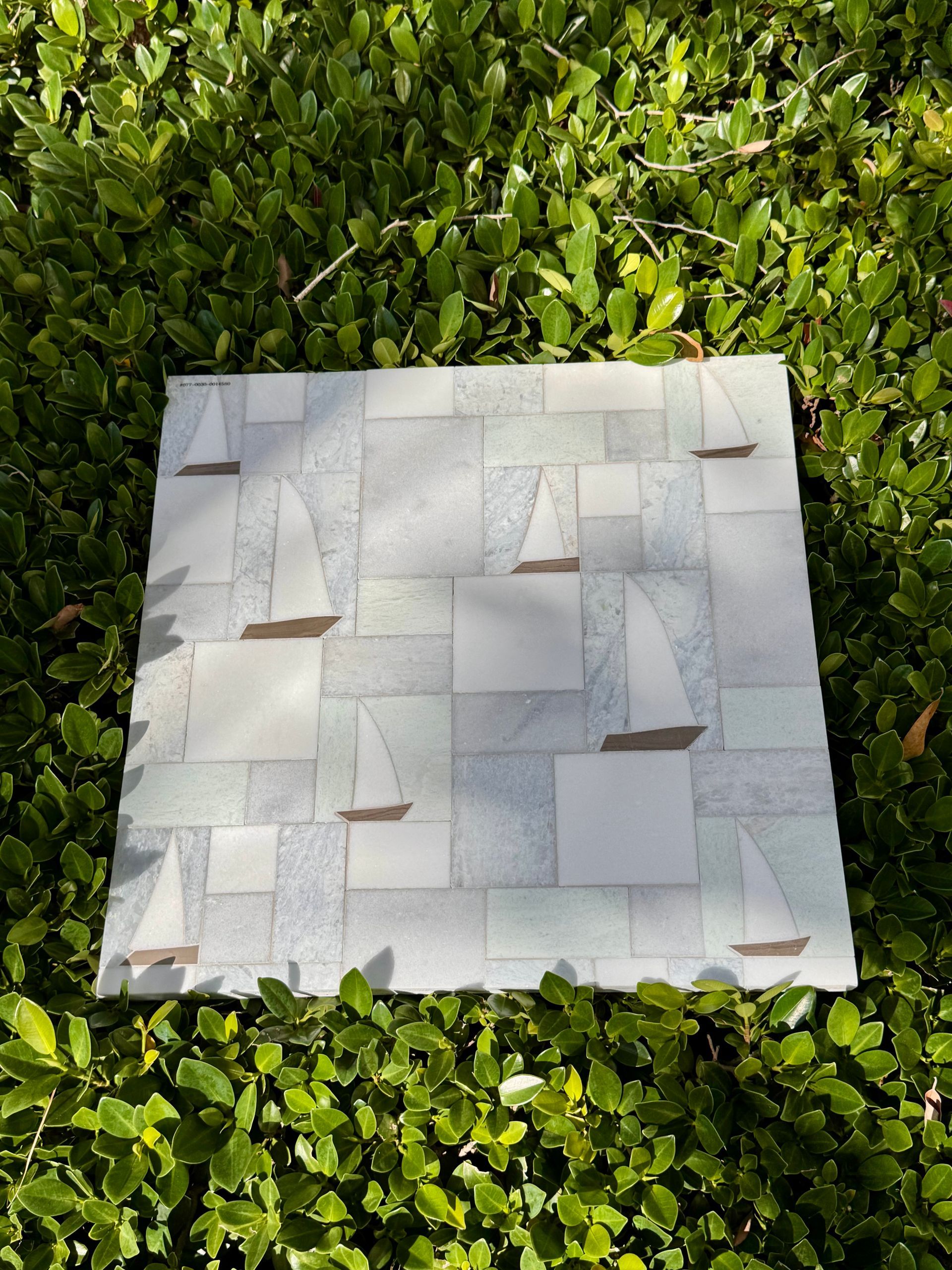 White woven square mat centered on green ivy ground cover, with small triangular flap details.