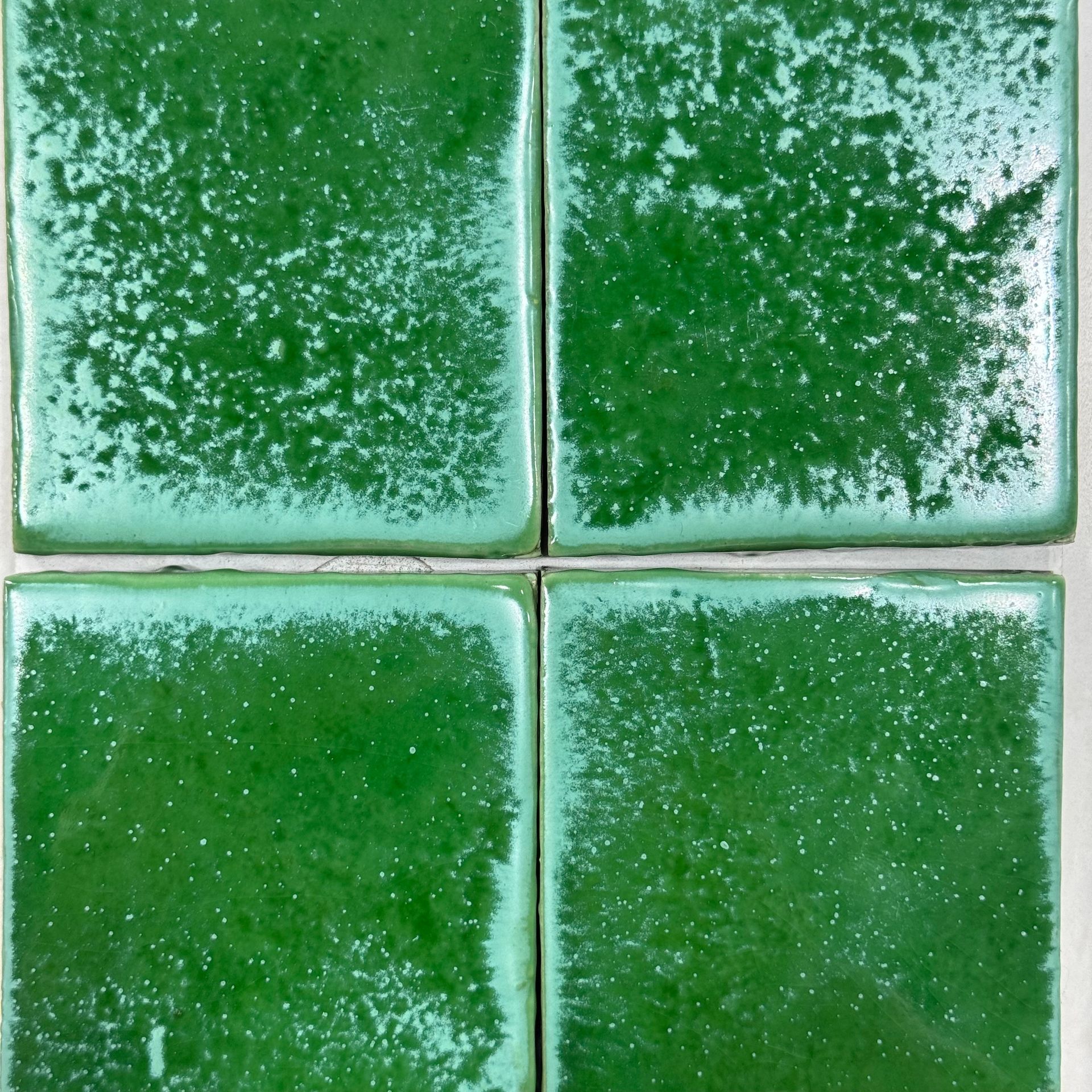 Four green glazed ceramic tiles with a white grout cross in the center