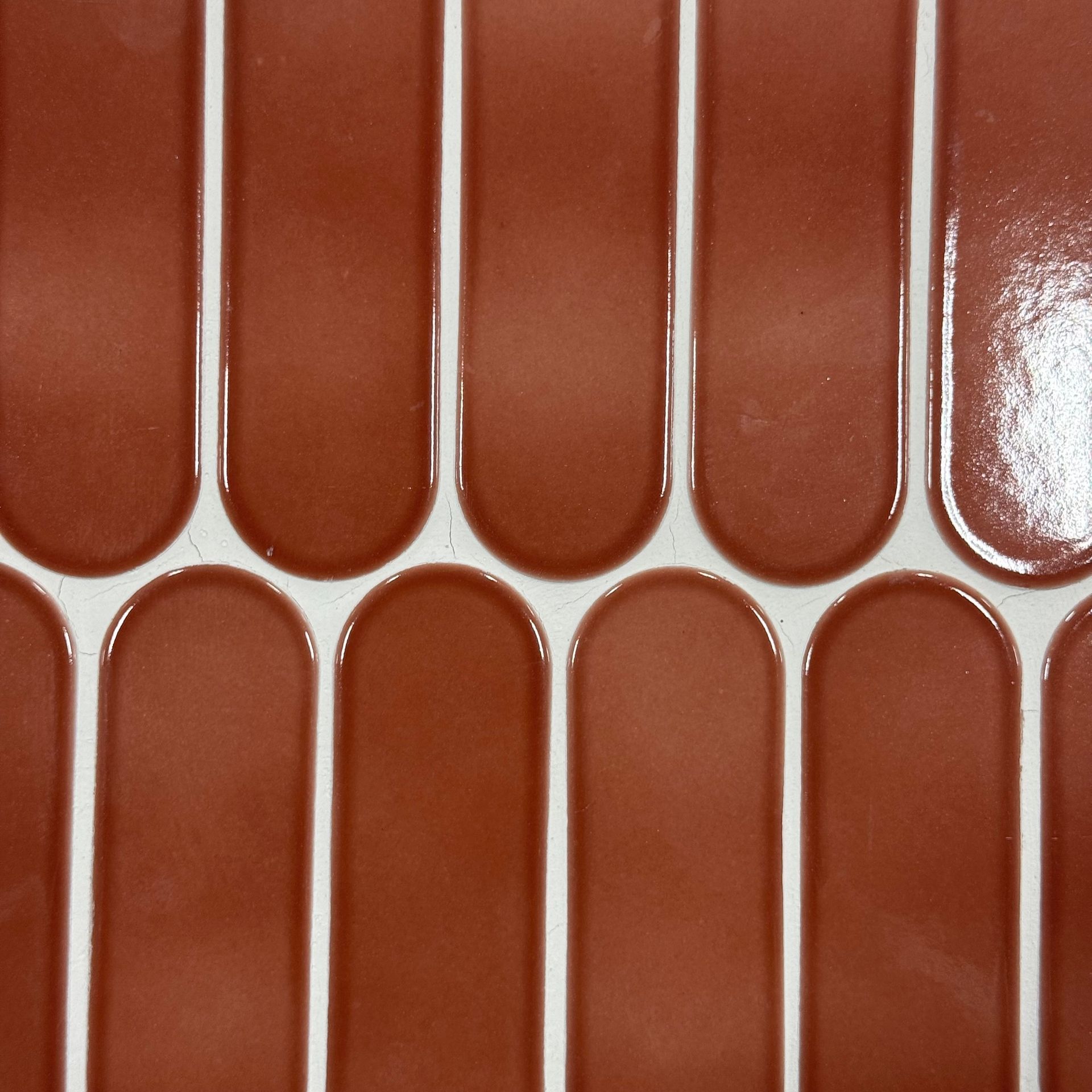 Close-up of glossy terracotta tiles with rounded vertical rectangles arranged in rows
