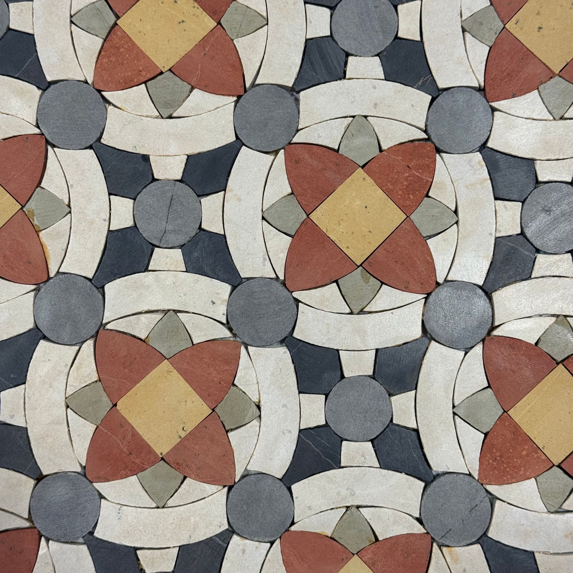 Abstract geometric mosaic of red, beige, gray, and white tiled circles and diamond shapes