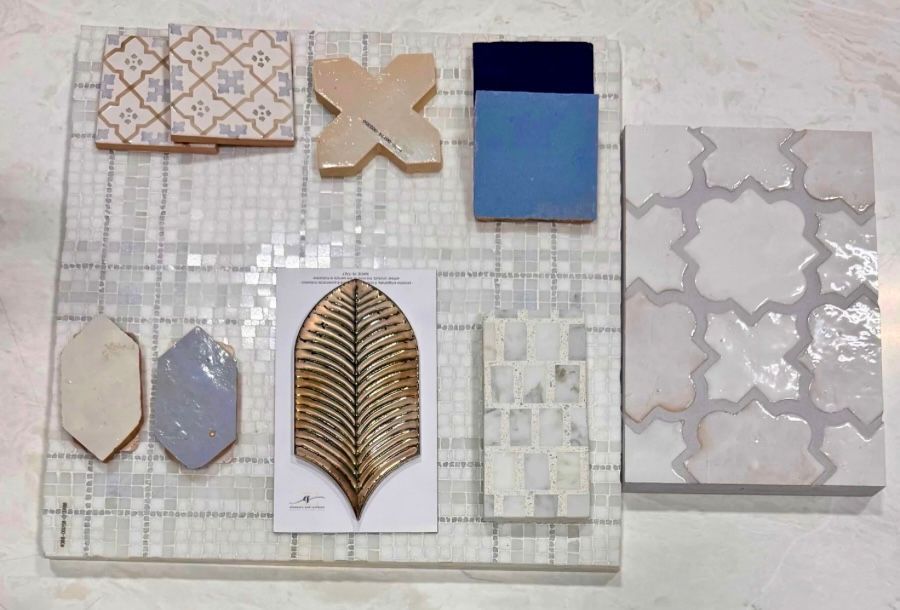Sample tile and pattern swatches arranged on a light grid board, with beige, blue, and metallic leaf motifs.