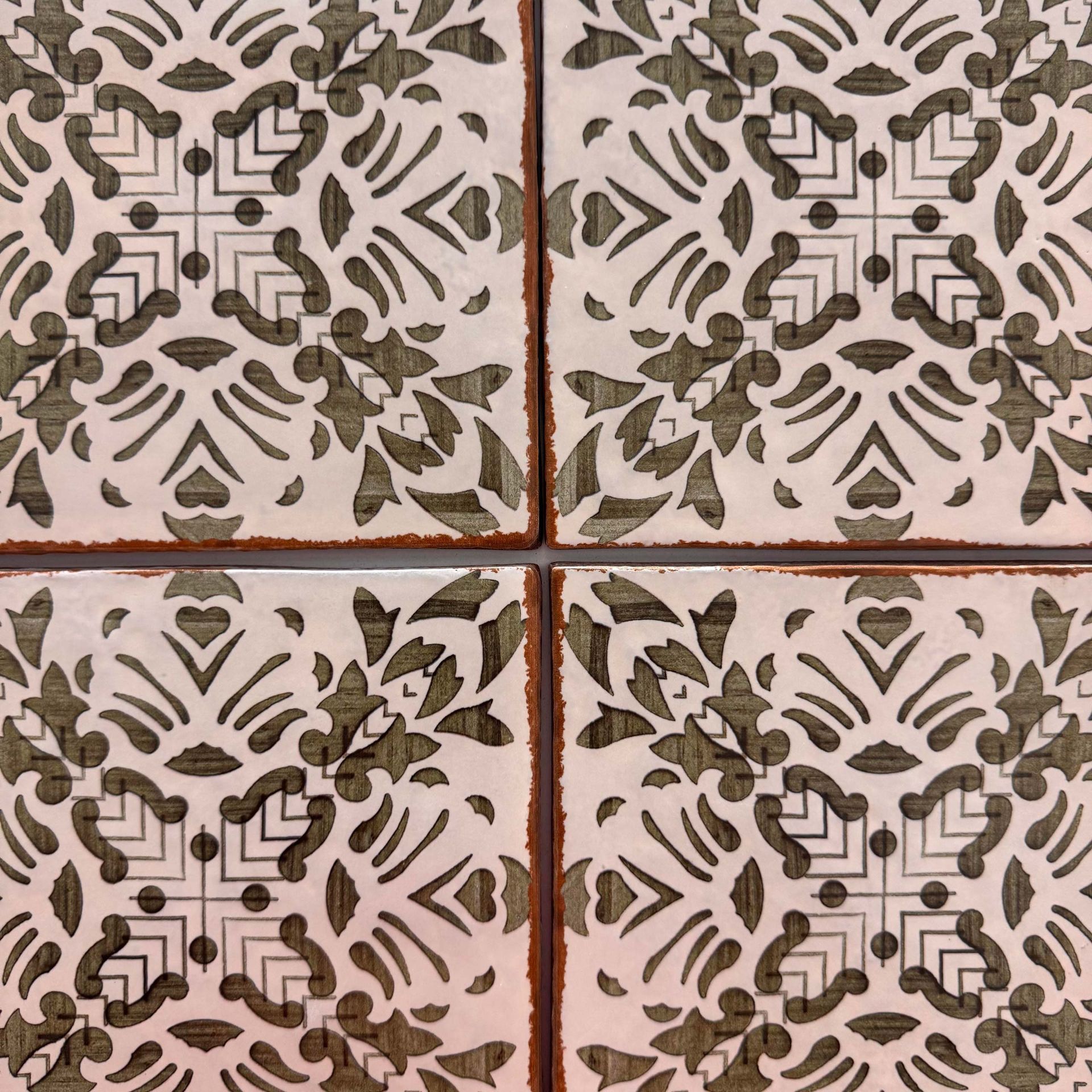 Four decorative floral tiles in beige and brown, arranged in a 2x2 grid with cross-shaped grout lines.