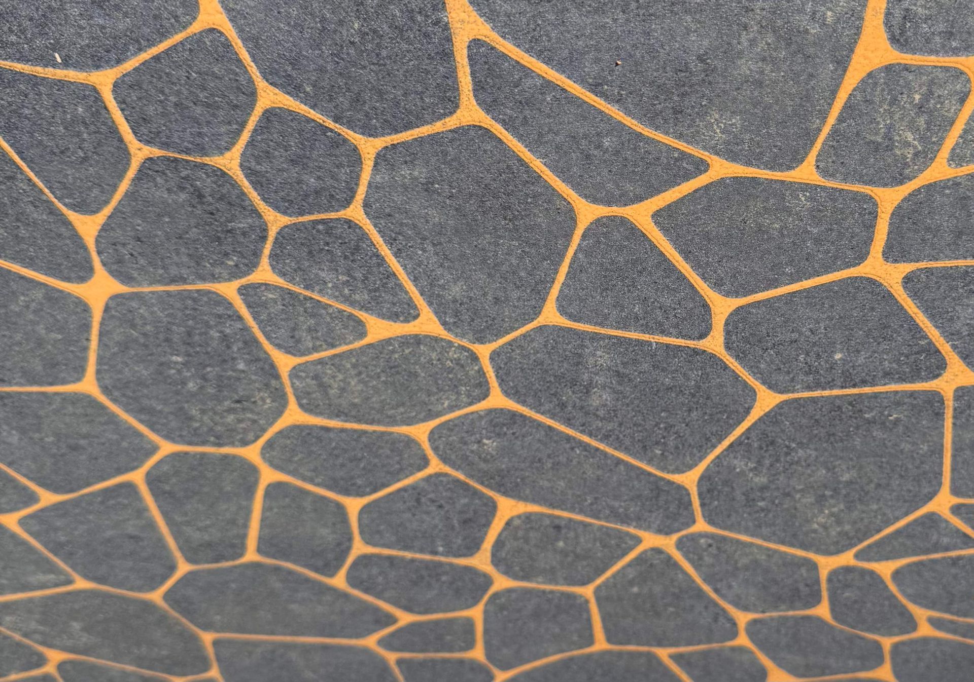 Gray stone surface with orange, cracked vein-like lines resembling a mosaic pattern