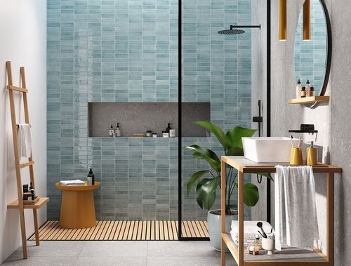 Modern bathroom with glass shower, blue tile walls, wood accents, and a plant beside a vanity.