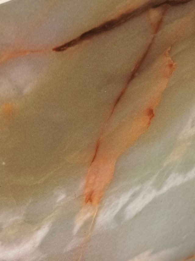 Close-up of a pale surface with a thin orange streak and a dark brown line