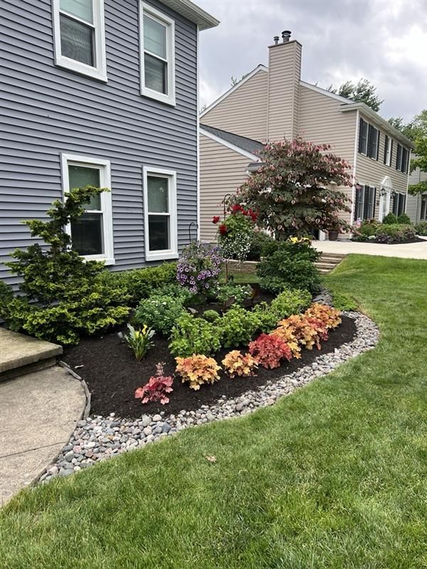 A house with a lush green lawn and a garden in front of it.