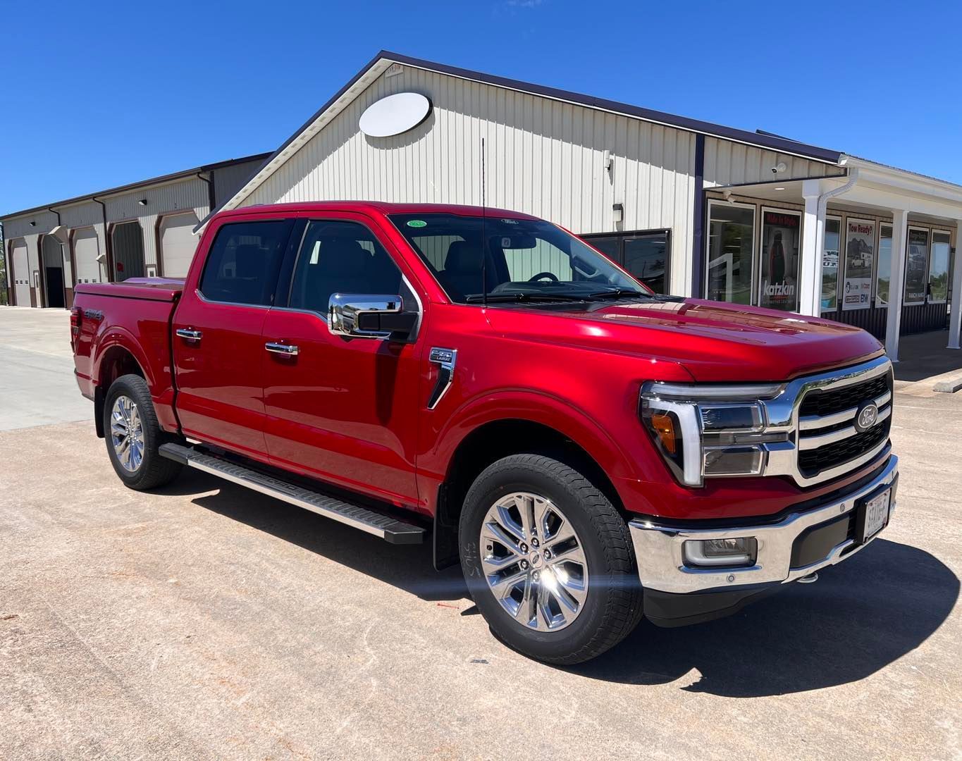 Red Ford F-150 truck parked in front of a building on a sunny day.
