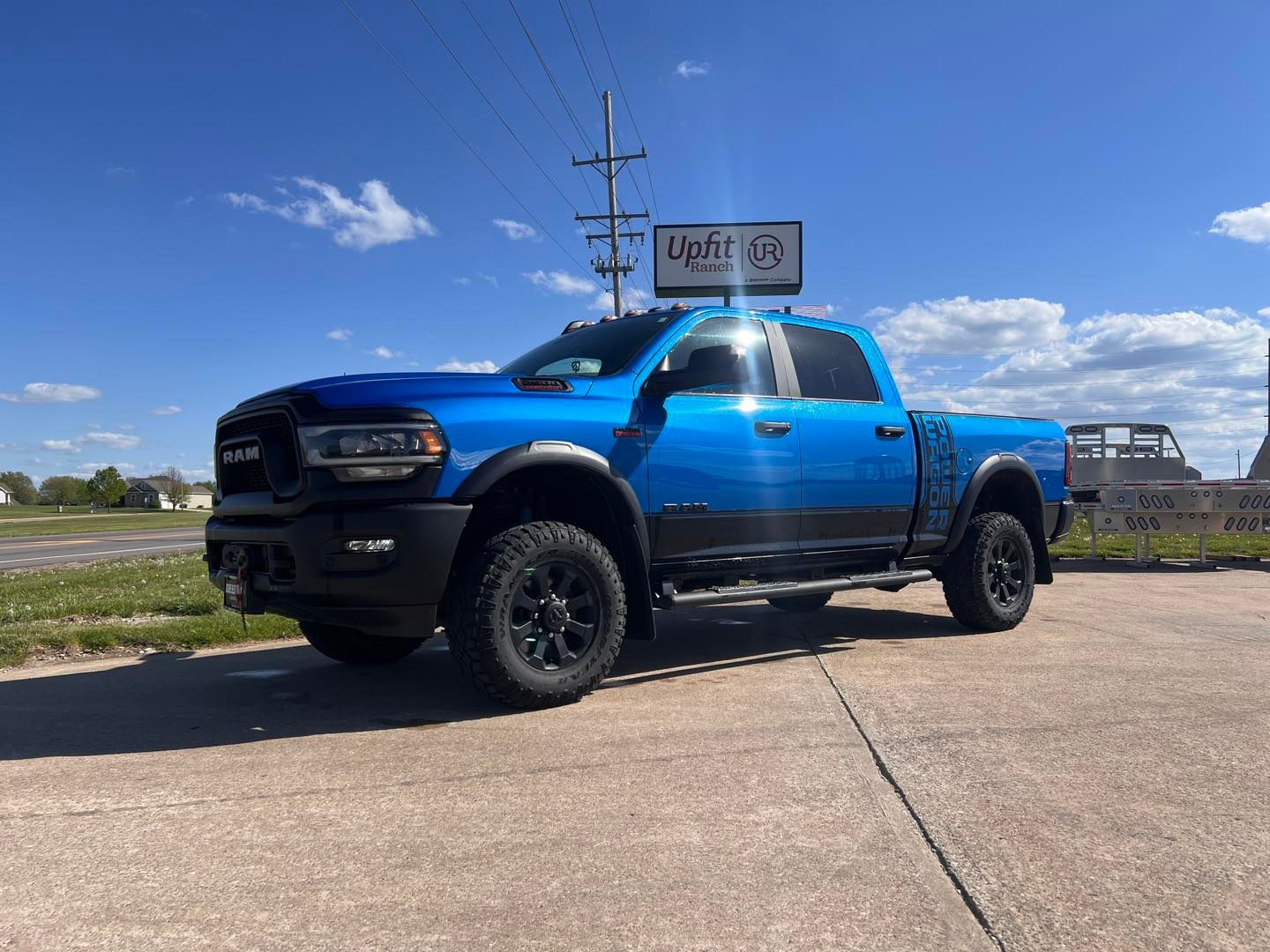 Blue Ram Power Wagon truck parked in front of a business on a sunny day.