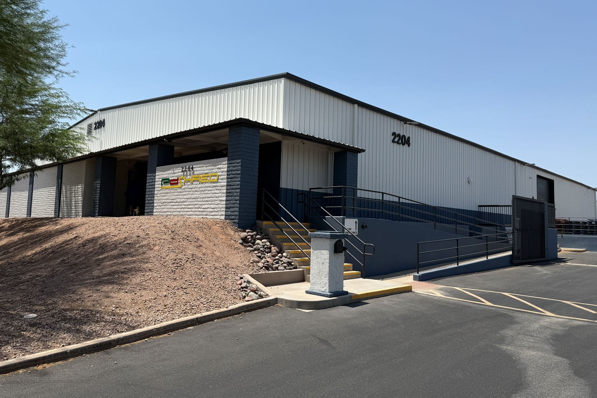 Warehouse building with a ramp and steps. Exterior view, blue and white color scheme.