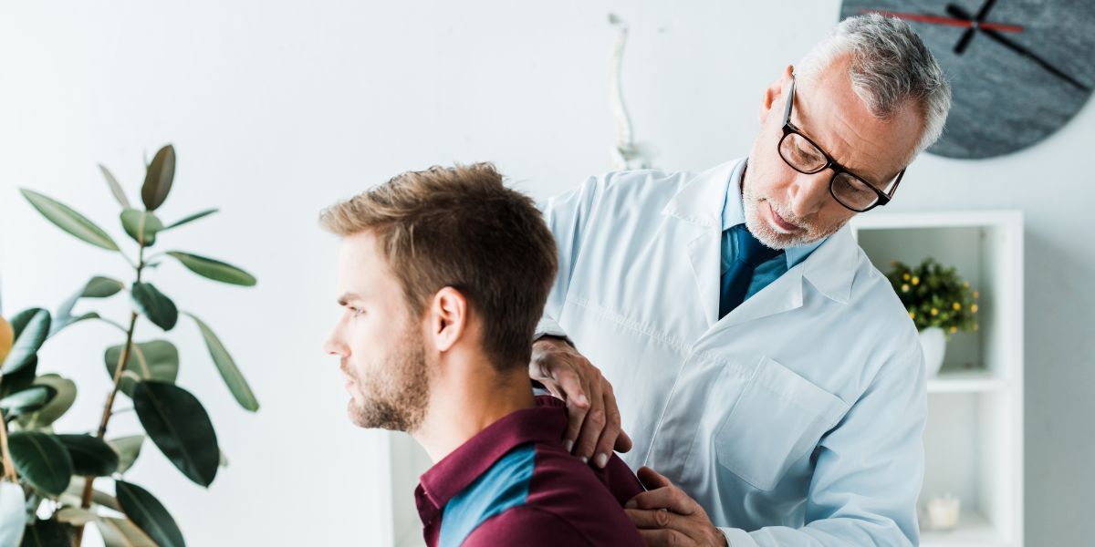 Doctor examining a patient's back in an office setting.