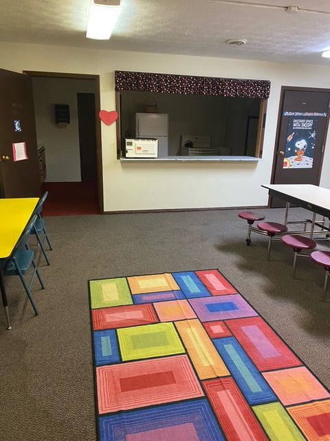 A room with tables and chairs and a colorful rug