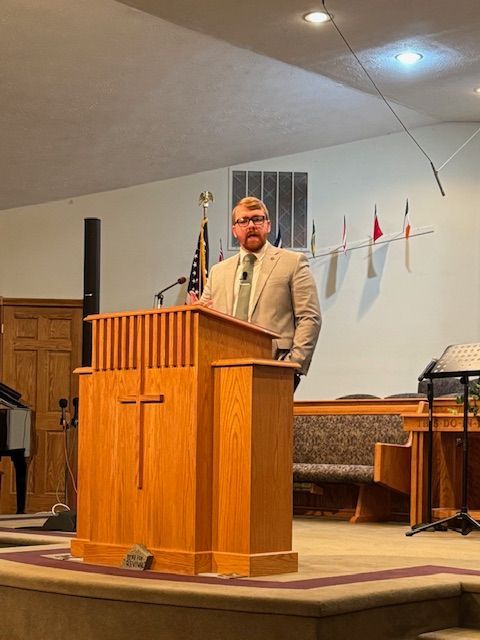 A man is standing at a podium in a church giving a speech.