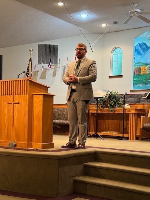 A man in a suit and tie is standing at a podium in a church.