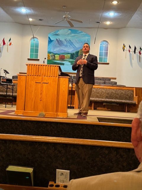 A man in a suit and tie stands at a podium in a church
