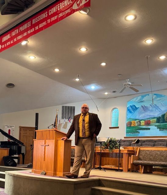 A man stands at a podium in a church with a banner that says missions conference