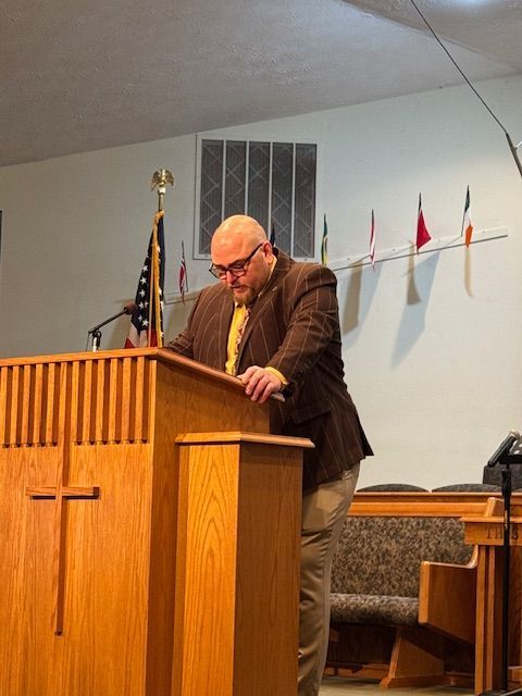 A man stands at a podium with a cross on it