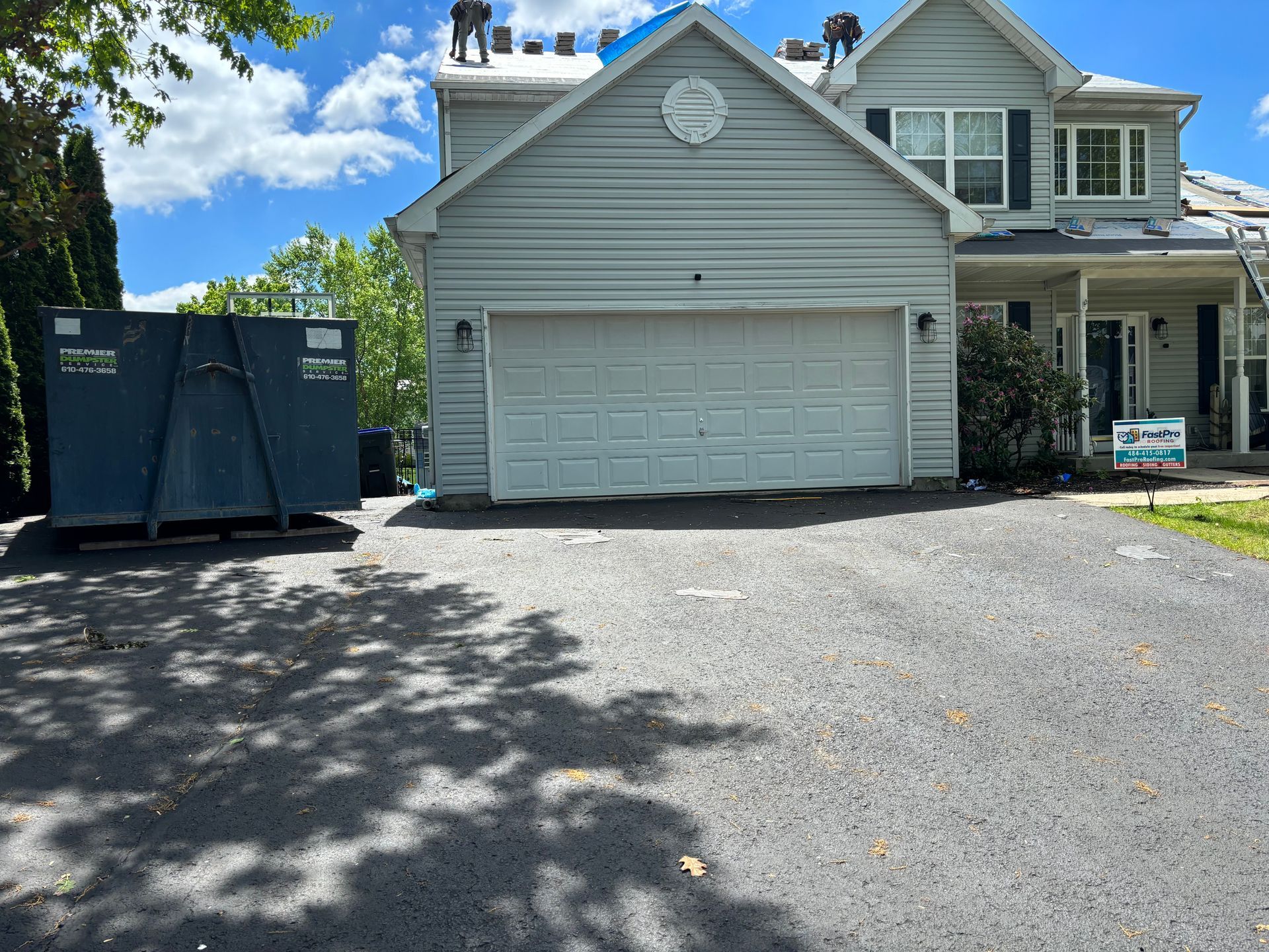 A large white house with a blue dumpster in front of it