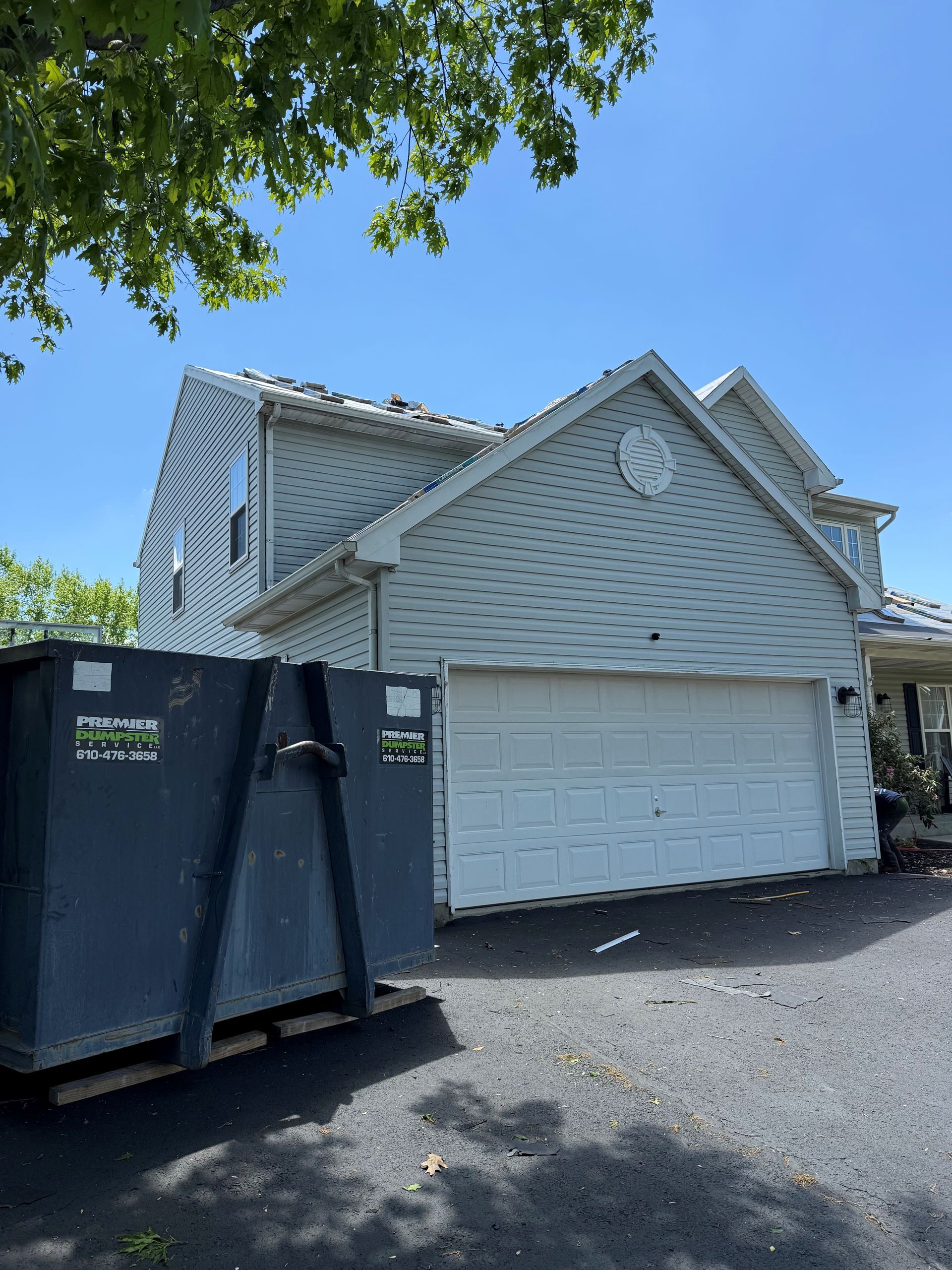 A large white house with a dumpster in front of it