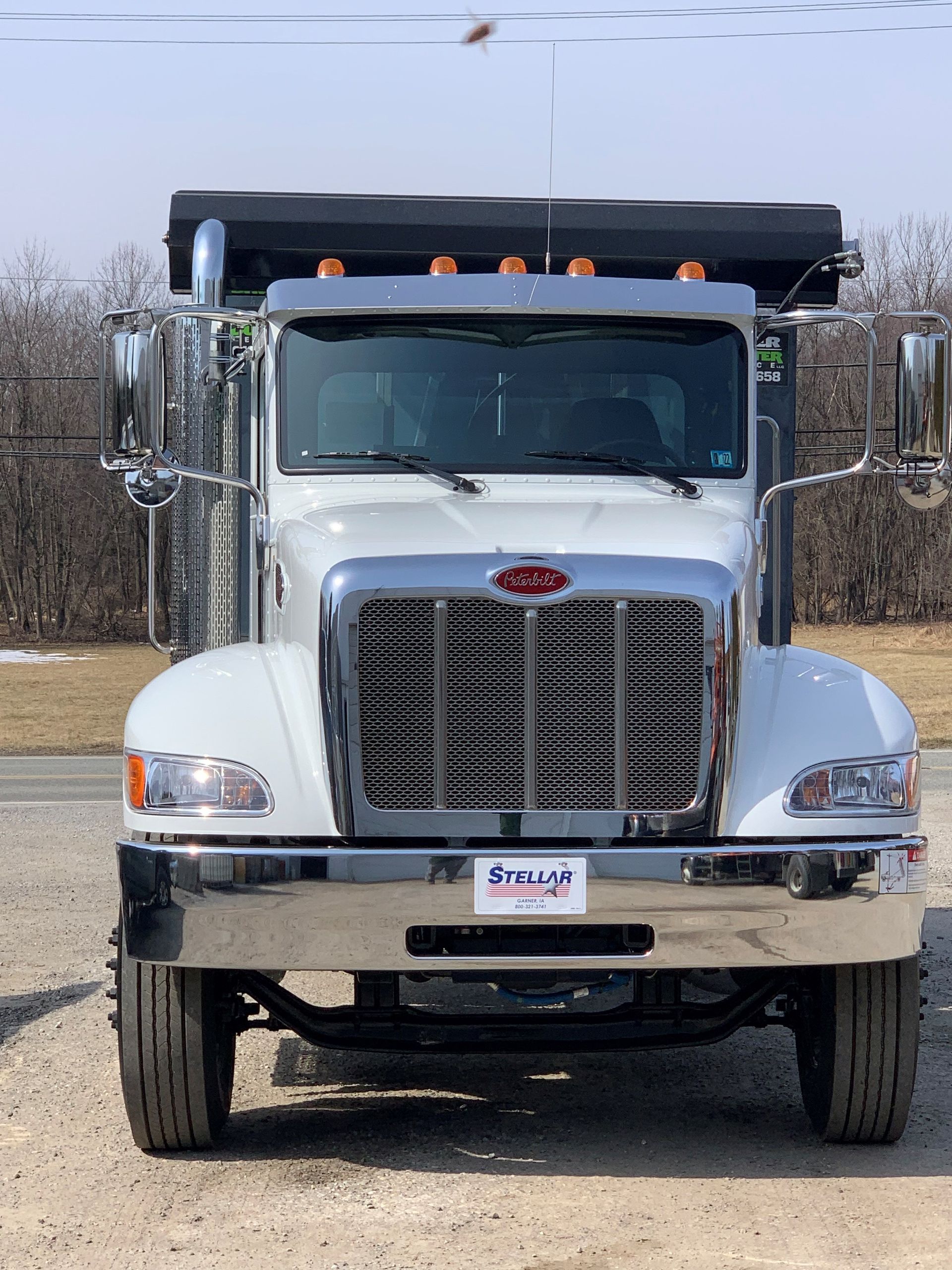 A white dump truck is parked on the side of the road.