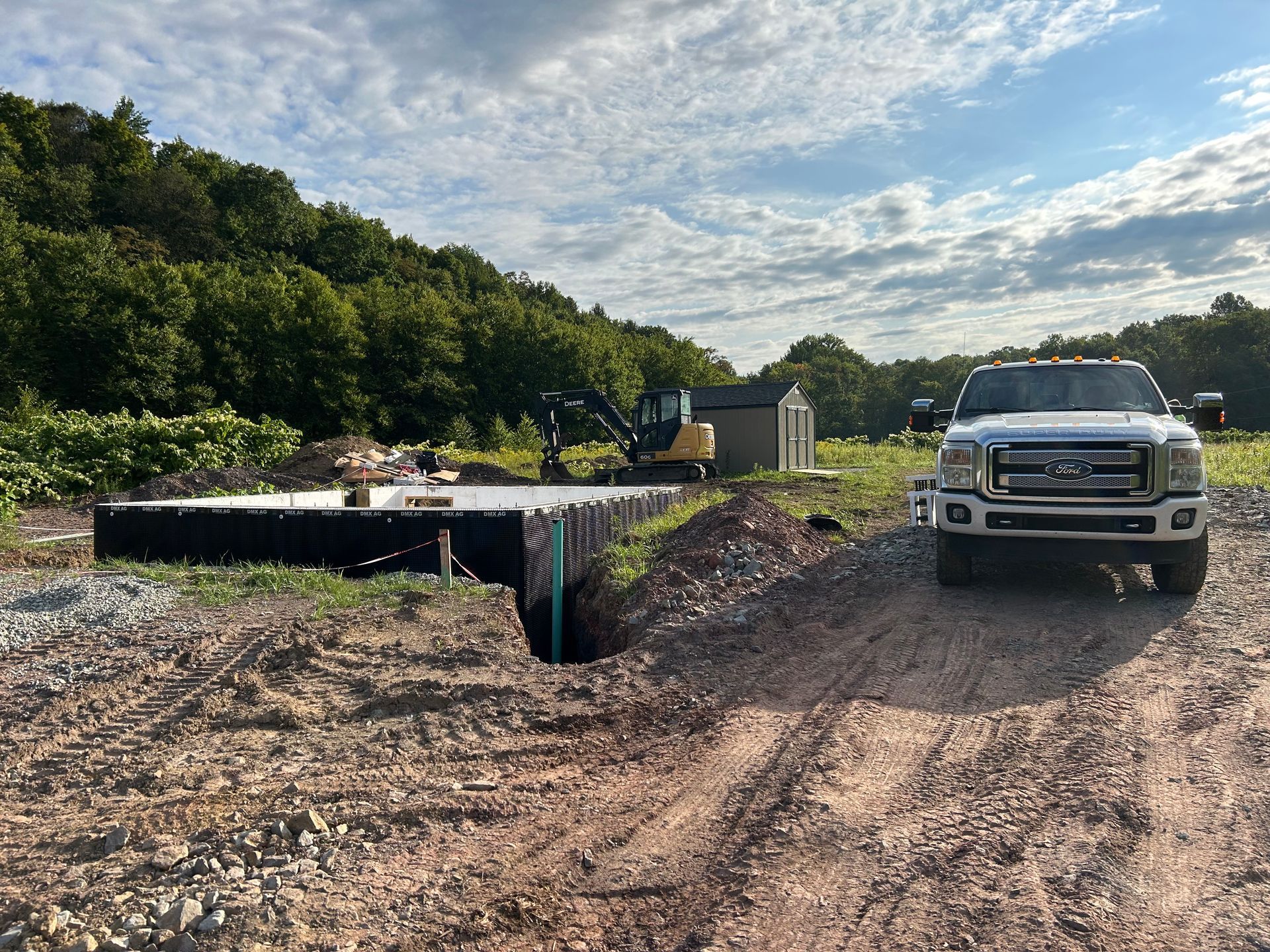 A white truck is parked on the side of a dirt road.