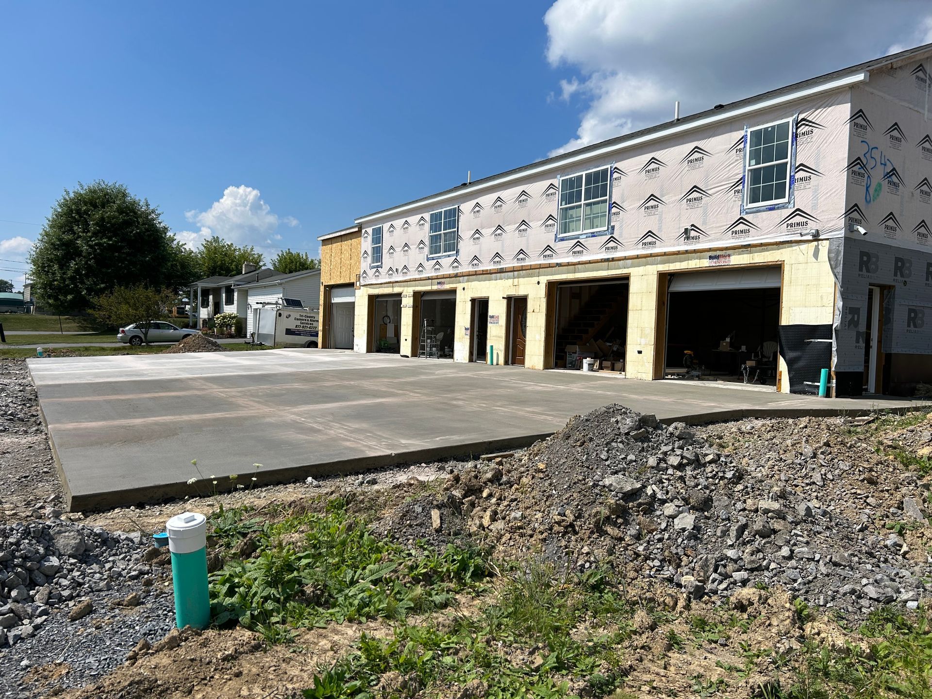 A building under construction with a concrete driveway in front of it.